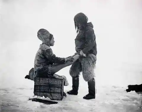An Inuit man warms up his wife’s feet in Greenland, 1890s. (photo by Robert E. Peary)